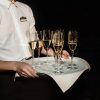 waiter holding tray with stylish glasses with champagne at evening wedding ceremony, catering